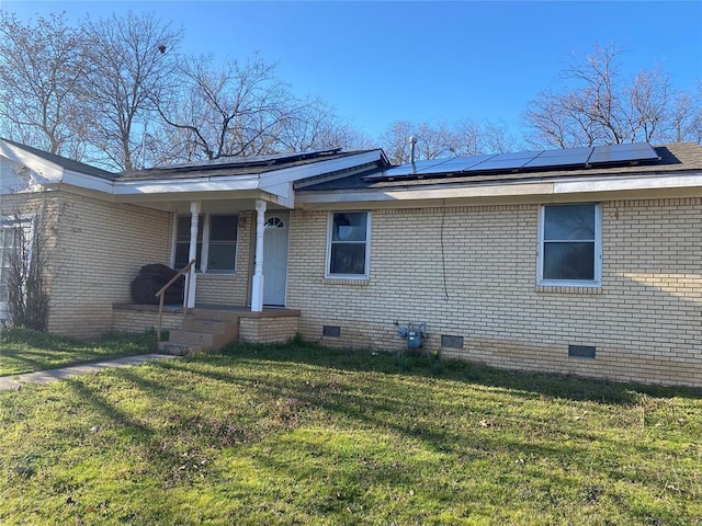 exterior space featuring a front yard, covered porch, crawl space, brick siding, and roof mounted solar panels