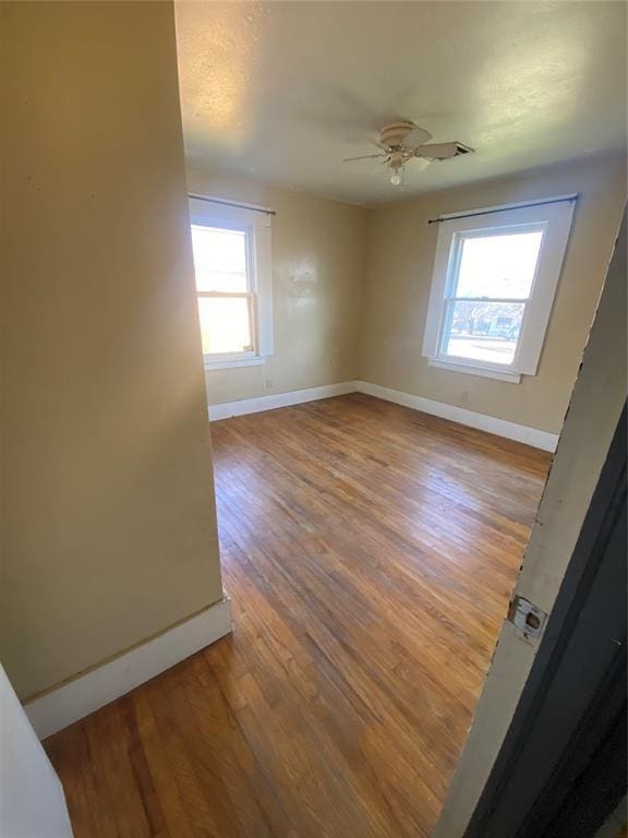 empty room with ceiling fan, baseboards, and wood finished floors