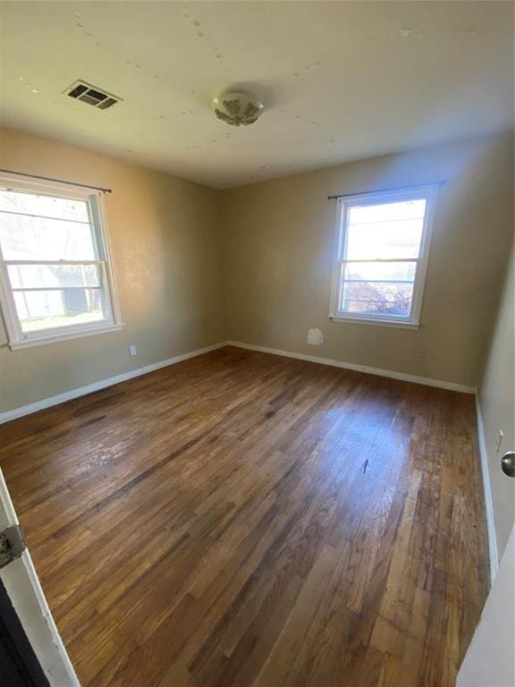 unfurnished room with visible vents, baseboards, and wood finished floors