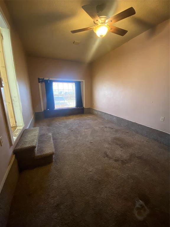 carpeted empty room with baseboards, a textured ceiling, a ceiling fan, and vaulted ceiling