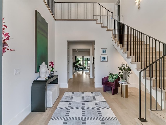 foyer entrance featuring a towering ceiling and light hardwood / wood-style flooring