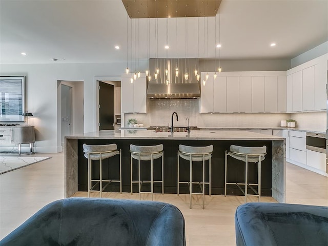 kitchen with a breakfast bar area, sink, hanging light fixtures, and a kitchen island with sink