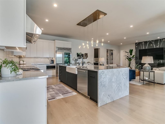 kitchen featuring extractor fan, white cabinetry, hanging light fixtures, appliances with stainless steel finishes, and a large island