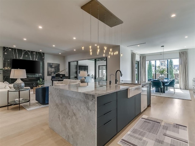 kitchen featuring light hardwood / wood-style floors, a spacious island, decorative light fixtures, dishwasher, and sink