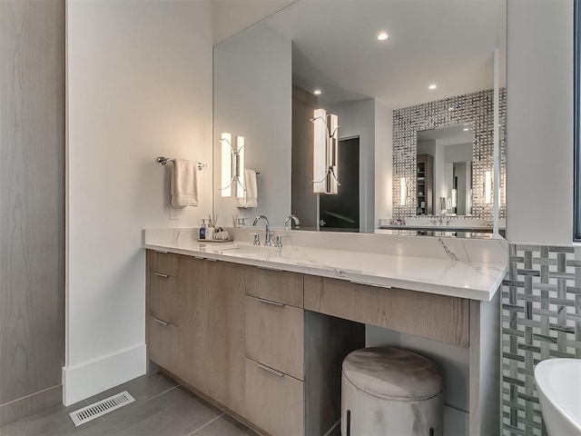 bathroom with tile walls, vanity, a bath, and tile patterned flooring