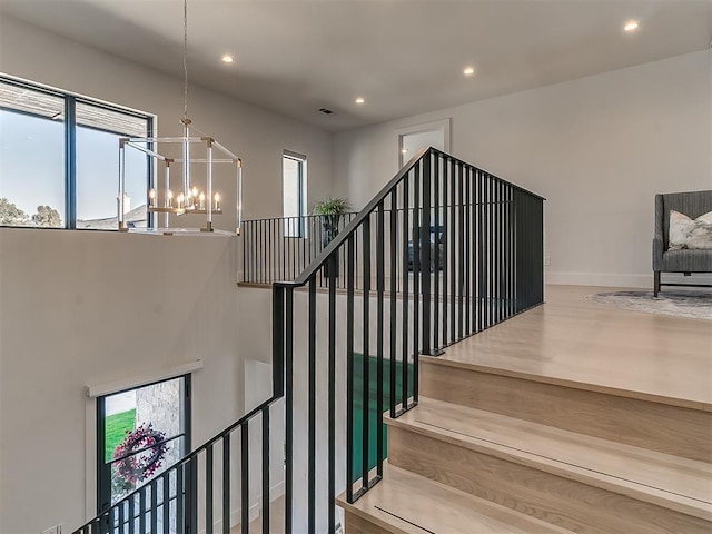 stairway with a wealth of natural light and a chandelier