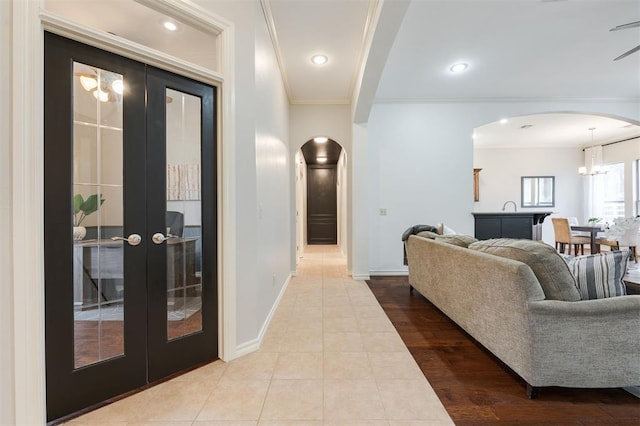 hallway featuring crown molding, light wood-type flooring, and french doors