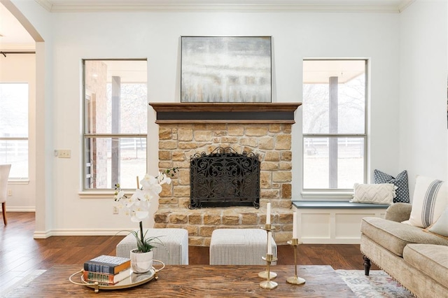 living room with a fireplace, ornamental molding, dark hardwood / wood-style floors, and a healthy amount of sunlight