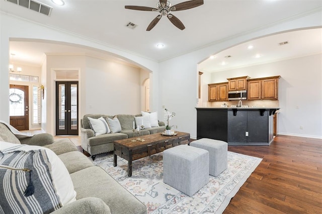 living room with crown molding, ceiling fan, and dark hardwood / wood-style flooring