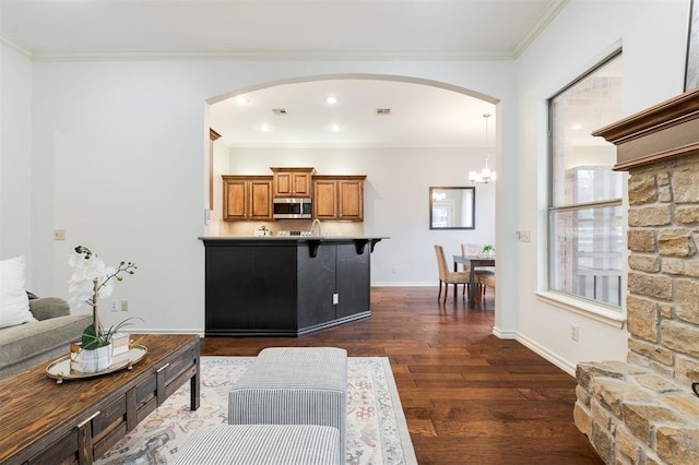 living room with crown molding, dark wood-type flooring, and a chandelier