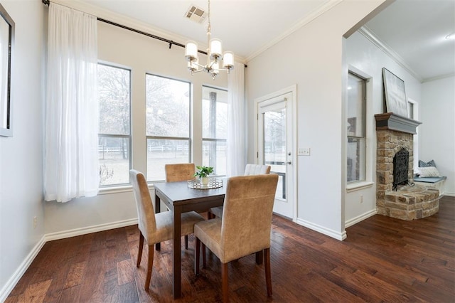 dining space featuring ornamental molding, dark hardwood / wood-style floors, a notable chandelier, and a fireplace