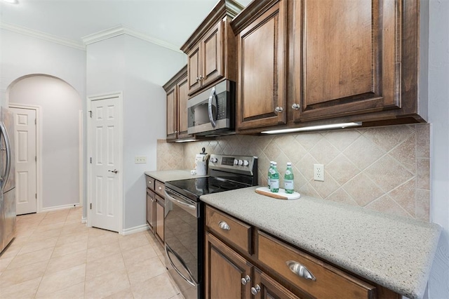 kitchen with stainless steel appliances, ornamental molding, backsplash, and light stone counters