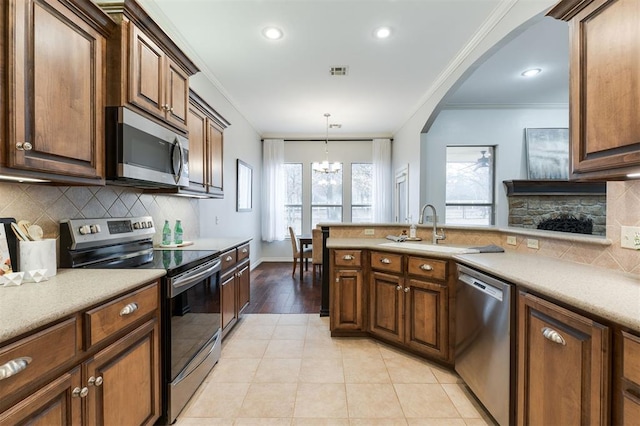 kitchen featuring hanging light fixtures, crown molding, appliances with stainless steel finishes, and decorative backsplash