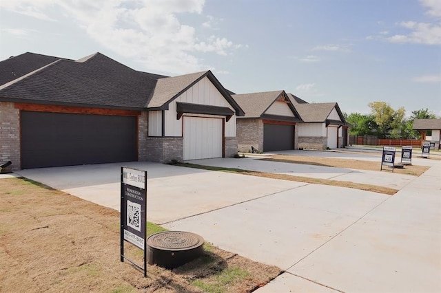 view of front of home with a shingled roof, driveway, brick siding, an attached garage, and fence