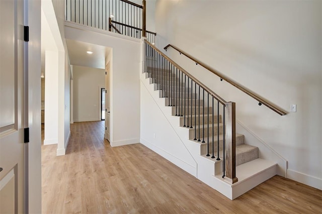 stairway with a high ceiling and wood-type flooring