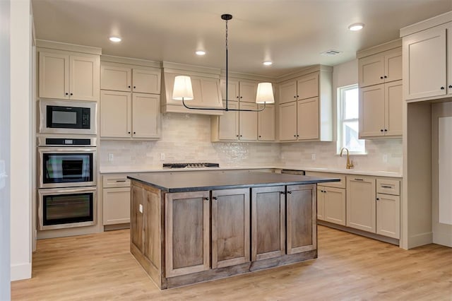 kitchen featuring a kitchen island, light hardwood / wood-style floors, hanging light fixtures, appliances with stainless steel finishes, and custom range hood