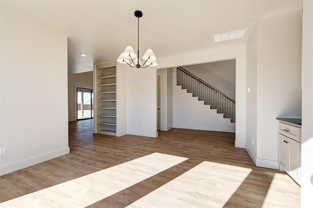 unfurnished dining area featuring wood-type flooring and a notable chandelier