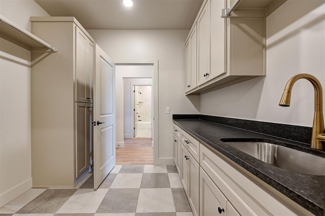 kitchen featuring sink, dark stone countertops, and white cabinetry