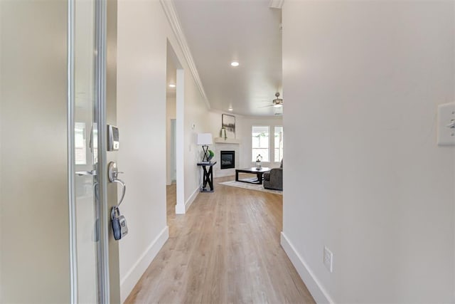 hall with ornamental molding and light hardwood / wood-style flooring