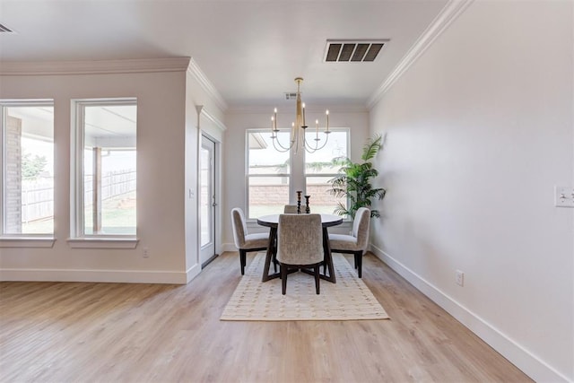 dining area featuring crown molding, light wood-type flooring, and an inviting chandelier