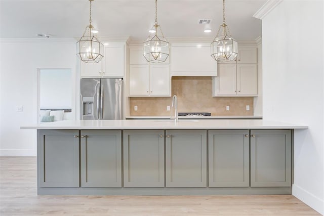 kitchen with stainless steel refrigerator with ice dispenser, crown molding, gray cabinetry, and decorative light fixtures