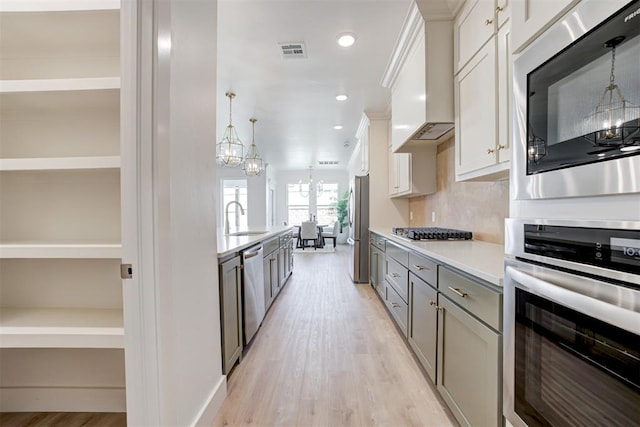 kitchen featuring stainless steel appliances, a chandelier, white cabinetry, and sink