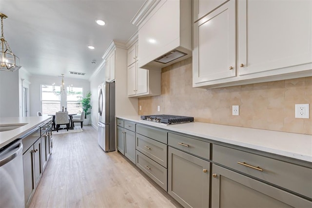 kitchen featuring light wood-type flooring, gray cabinetry, stainless steel appliances, and pendant lighting