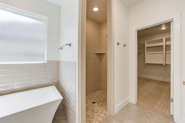 bathroom with tile walls and separate shower and tub