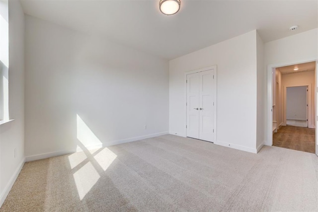 unfurnished bedroom with a closet and light colored carpet