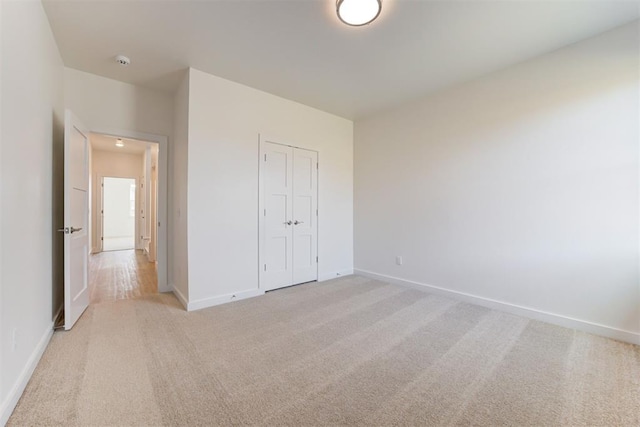 unfurnished bedroom featuring a closet and light colored carpet