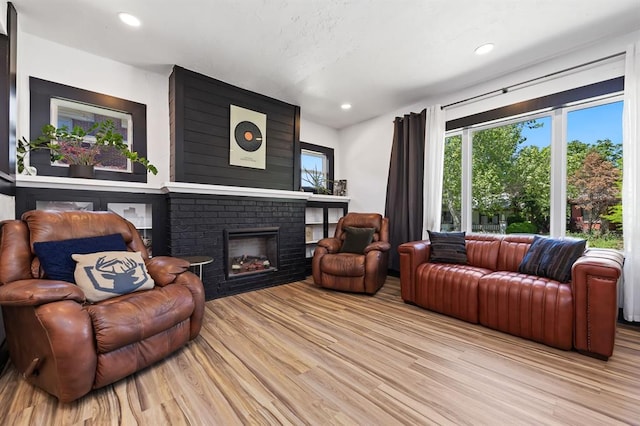 living room with a brick fireplace and light hardwood / wood-style flooring