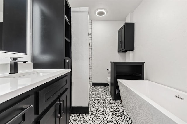 bathroom featuring a relaxing tiled tub, vanity, tile patterned floors, and toilet