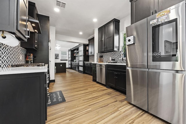 kitchen featuring stainless steel appliances, decorative backsplash, and light hardwood / wood-style flooring