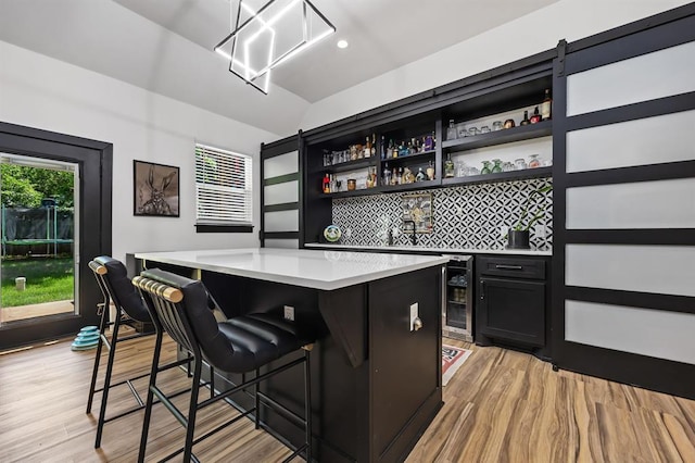 bar with tasteful backsplash, beverage cooler, and light hardwood / wood-style floors