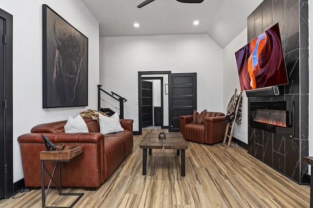 living room with ceiling fan, lofted ceiling, a fireplace, and light hardwood / wood-style flooring