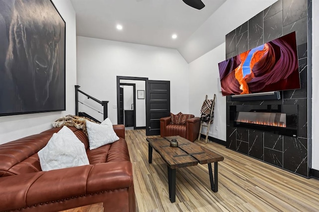 living room featuring a fireplace, vaulted ceiling, and light wood-type flooring