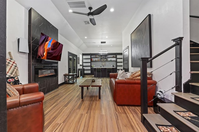 living room with ceiling fan, a tile fireplace, and light wood-type flooring