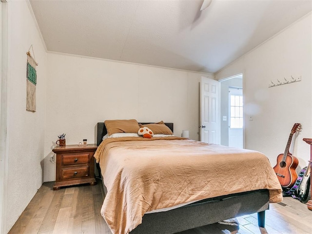 bedroom with vaulted ceiling, ornamental molding, and hardwood / wood-style flooring