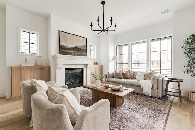 living room featuring light wood-type flooring, plenty of natural light, and a chandelier