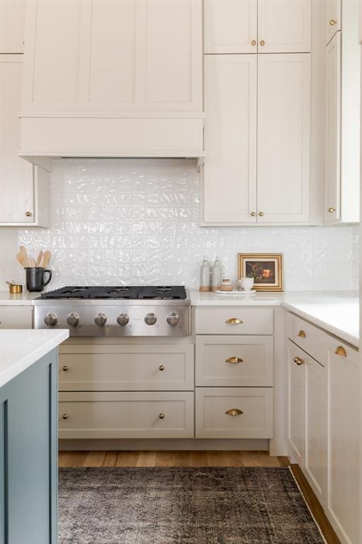 kitchen with stainless steel gas stovetop, dark hardwood / wood-style floors, white cabinets, and backsplash