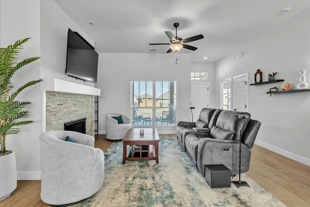 living room with hardwood / wood-style flooring, ceiling fan, and a fireplace