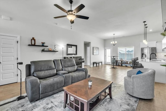 living room with ceiling fan with notable chandelier and sink