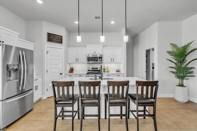 kitchen with a kitchen island with sink, sink, stainless steel appliances, and white cabinets