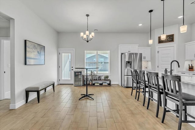 interior space featuring a breakfast bar, pendant lighting, white cabinets, decorative backsplash, and stainless steel fridge with ice dispenser