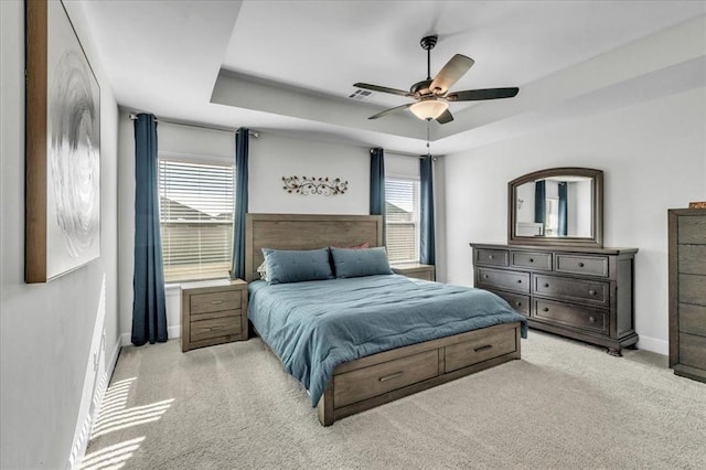 carpeted bedroom featuring ceiling fan and a tray ceiling