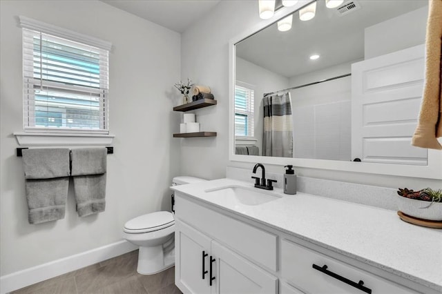 bathroom with vanity, a wealth of natural light, toilet, and walk in shower