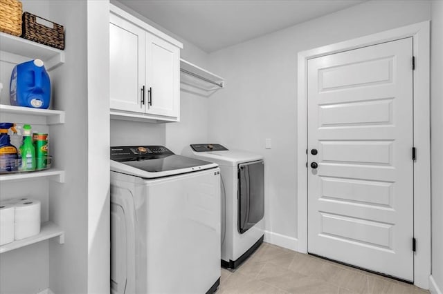 laundry area with washer and clothes dryer, cabinets, and light tile patterned flooring