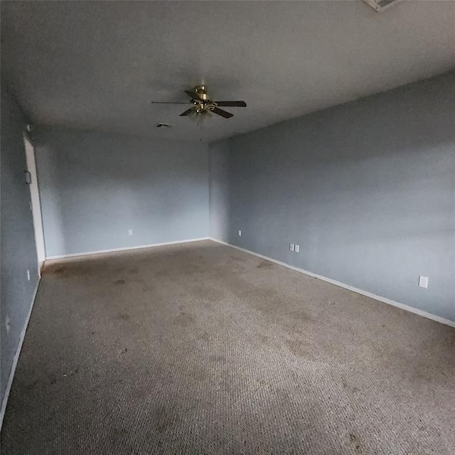 unfurnished room with carpet floors, visible vents, ceiling fan, and baseboards