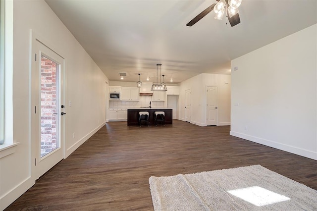 unfurnished living room featuring ceiling fan, sink, and dark hardwood / wood-style flooring