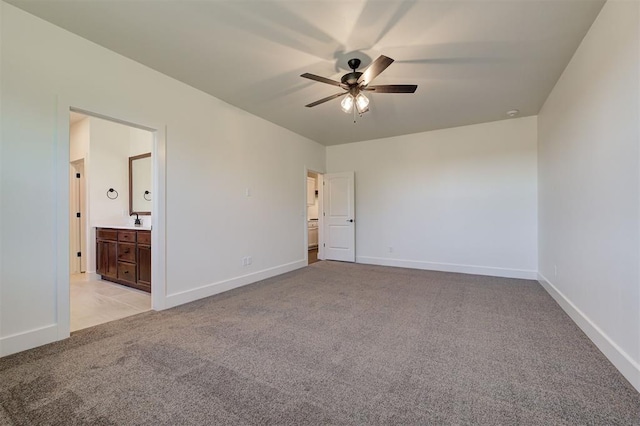 unfurnished bedroom featuring ceiling fan, light colored carpet, and ensuite bath